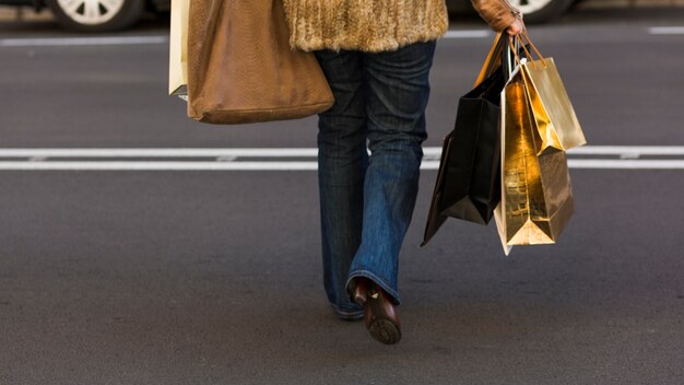 Vrouw die straat met het winkelen zakken kruist