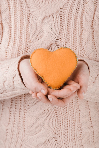 Vrouw die sweater draagt die oranje hart houdt