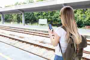 Gratis foto vrouw die telefoon erachter bekijkt van