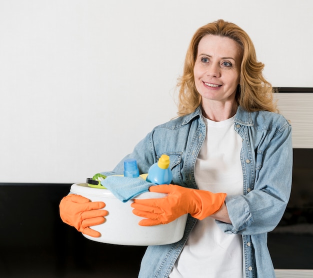 Vrouw die terwijl het houden van mand schoonmakende producten stellen