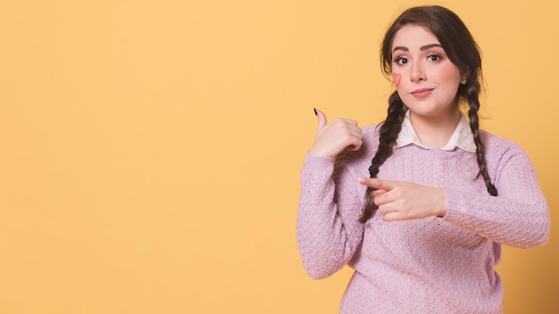 Gratis foto vrouw die terwijl het tonen van iets achter haar stelt