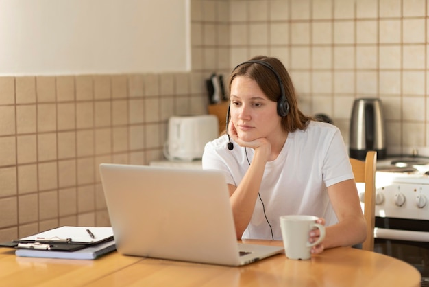 Vrouw die thuis in de keuken werkt tijdens quarantaine met laptop