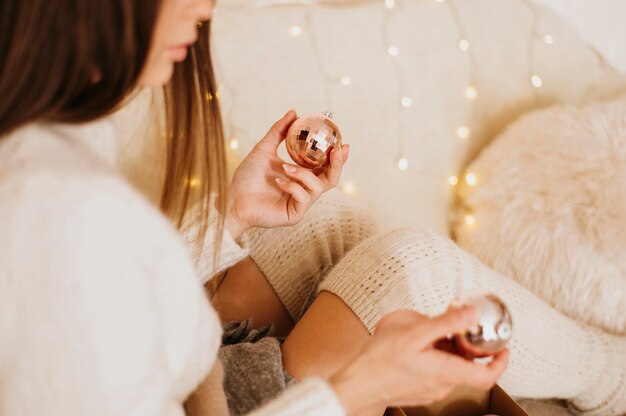 Vrouw die thuis ontspant en decoratieve boomballen houdt