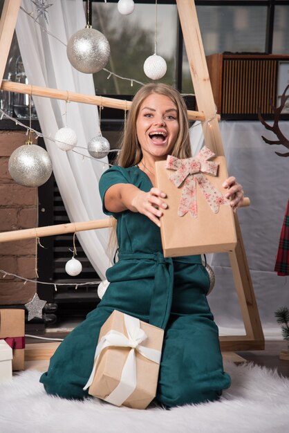 Vrouw die thuis op de grond zit met kerstcadeautjes