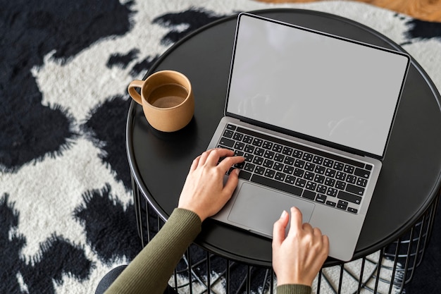 Vrouw die thuis werkt op een laptop met leeg scherm