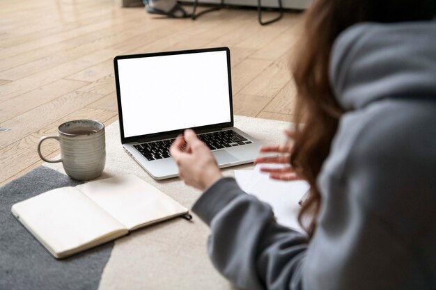 Vrouw die vanuit huis op de vloer werkt met apparaat