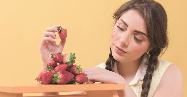 Gratis foto vrouw die verleidelijk aardbeien bekijken