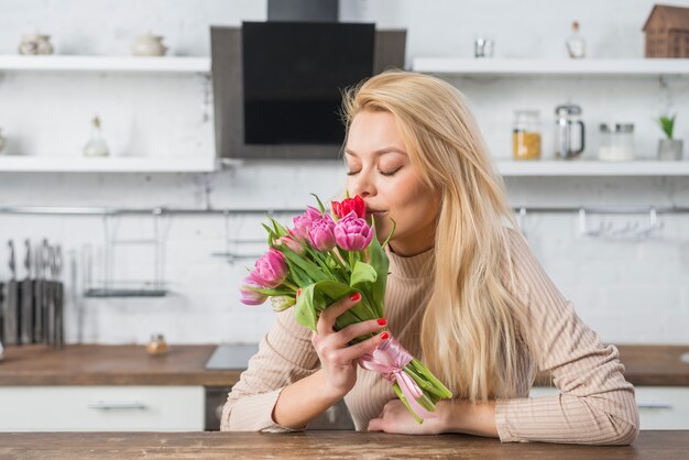 Vrouw die verse bloemen in keuken ruikt