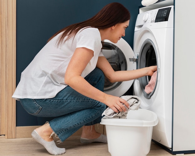 Vrouw die vuile kleren in de wasmachine doet