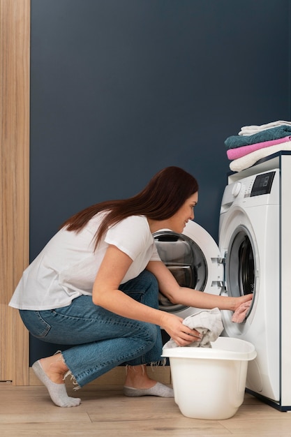 Vrouw die vuile kleren in de wasmachine doet