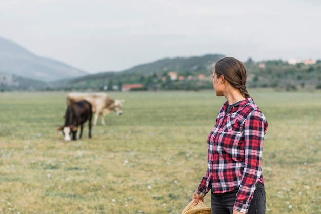 Vrouw die weidende koeien op het gebied bekijkt