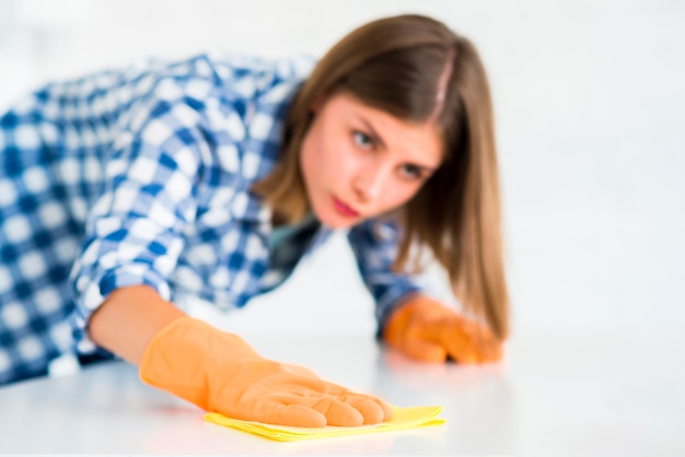 Vrouw die witte oppervlakte van het gele servet schoonmaakt