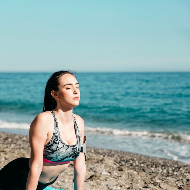 Vrouw die yoga doet bij het strand