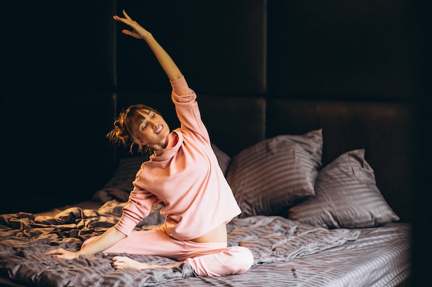 Vrouw die yoga in bed doet