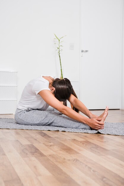 Vrouw die yoga thuis doet