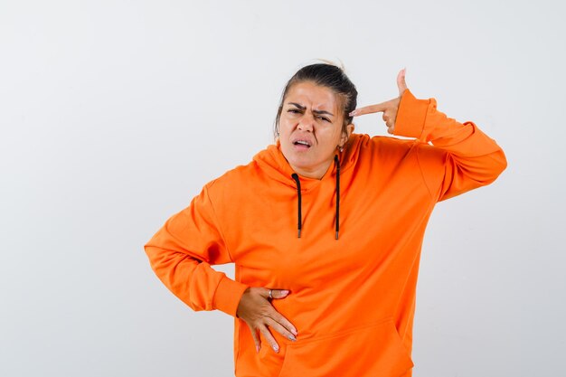 Vrouw die zelfmoordgebaar maakt in oranje hoodie en er hatelijk uitziet