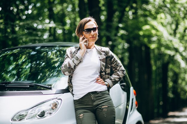 Vrouw die zich door de auto in park bevindt dat telefoon met behulp van