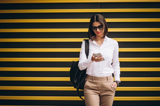 Vrouw die zich door de gele muur bevindt en op de telefoon spreekt