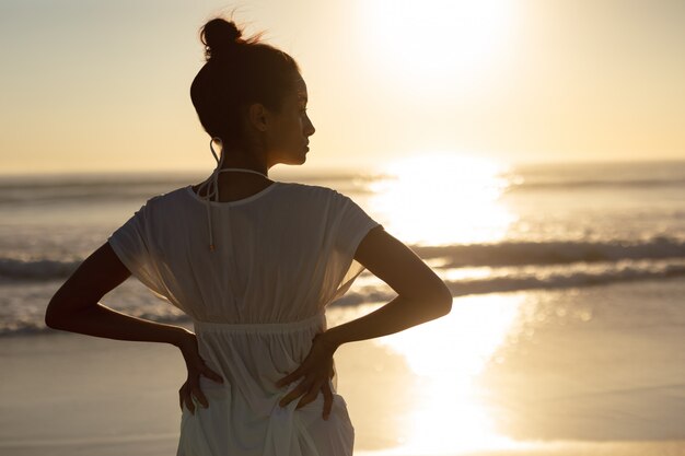 Gratis foto vrouw die zich met handen op heupen op het strand bevindt