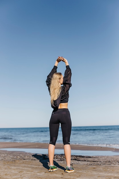 Gratis foto vrouw die zich uitstrekt op het strand