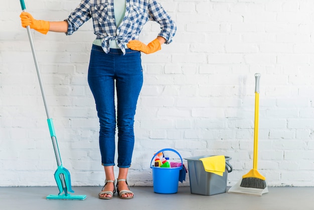 Vrouw die zich voor bakstenen muur met het schoonmaken van materiaal bevindt