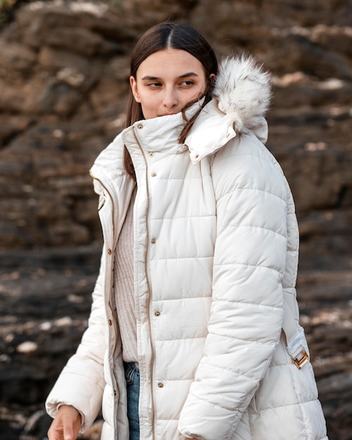 Vrouw die zich voordeed op het strand met winterjas