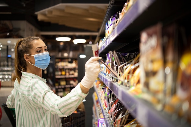 Vrouw die zichzelf beschermt tegen het coronavirus tijdens het winkelen in de supermarkt