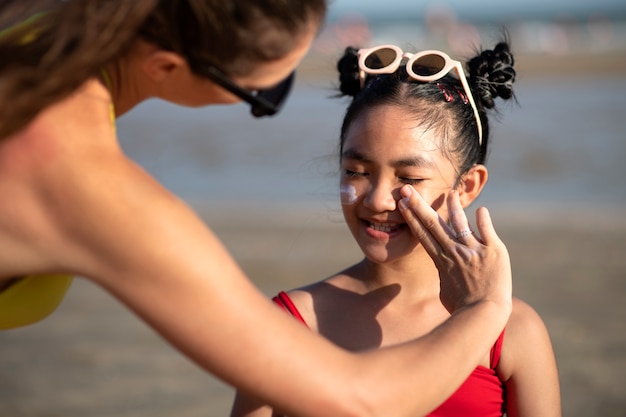 Vrouw die zonnebrandcrème toepast op het vooraanzicht van het kind