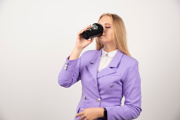 Vrouw die zwarte kop koffie drinkt op wit