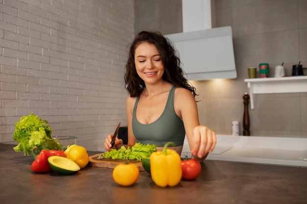 Gratis foto vrouw digitaal loskoppelen thuis door een gezonde groentesalade te maken