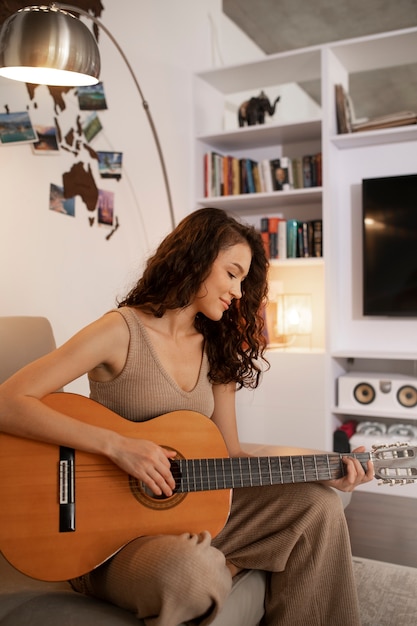 Vrouw digitaal loskoppelen thuis met gitaar