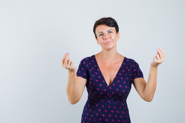 Vrouw doet geldgebaar in jurk en zoekt armoedig.