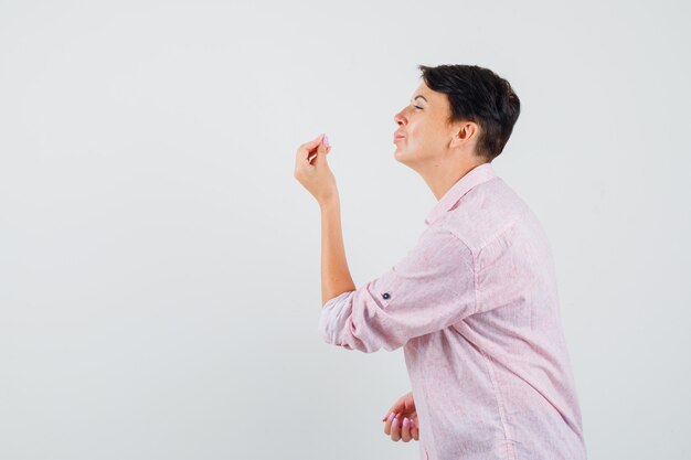 Vrouw doet Italiaans gebaar, ontevreden over domme vraag in roze shirt.