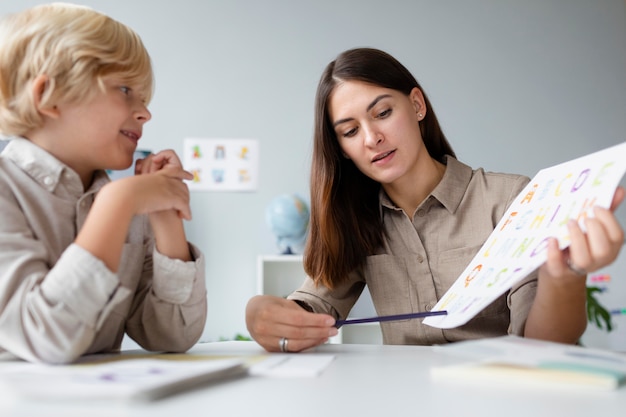 Vrouw doet logopedie met een kleine blonde jongen