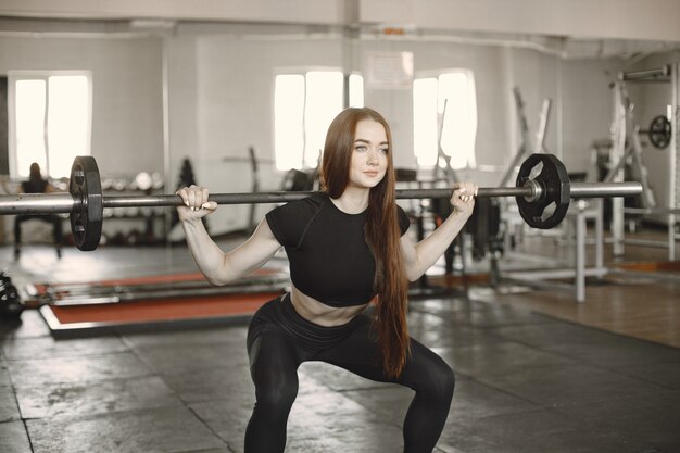 Vrouw doet oefening met barbell. Het dragen van zwarte actieve kleding.