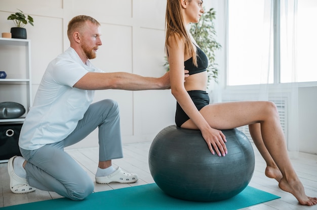 Gratis foto vrouw doet oefeningen met bal en fysiotherapeut