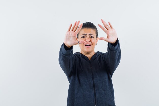 Vrouw doet stop gebaar in hoodie en kijkt geïrriteerd, vooraanzicht.