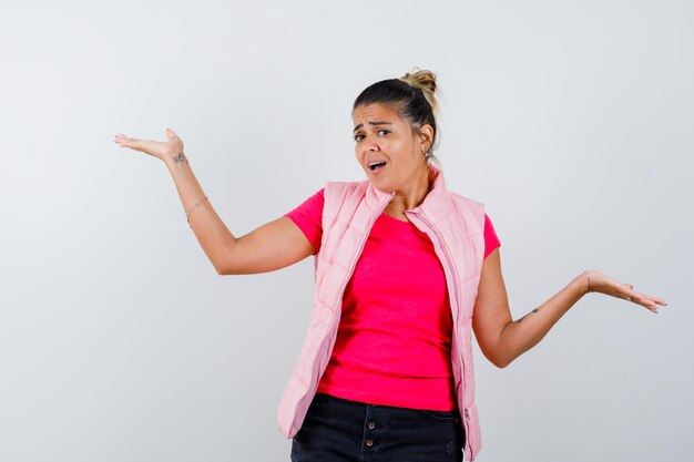 Vrouw doet welkomstgebaar in t-shirt, vest en ziet er zelfverzekerd uit