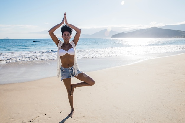 Vrouw doet yoga op het strand