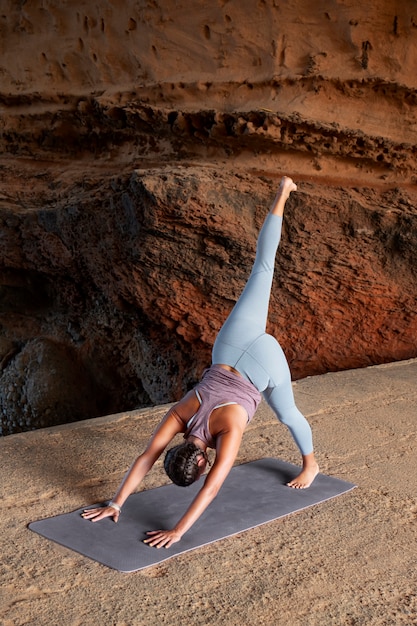 Vrouw doet yoga pose op mat full shot