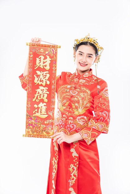 Vrouw draagt cheongsam-pak blij met het krijgen van de Chinese wenskaart van de baas in Chinees nieuwjaar