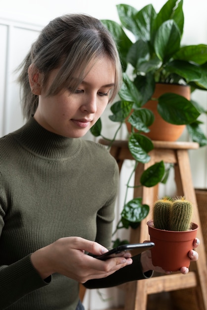 Vrouw draagt een cactus terwijl ze haar telefoon checkt