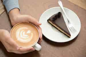 Gratis foto vrouw drinken cappuccino en eten cake