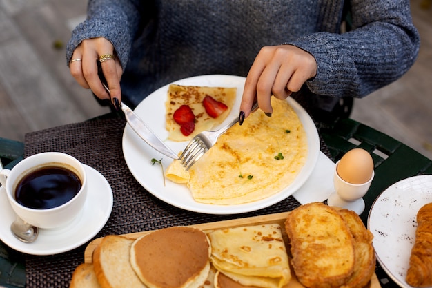 Vrouw eet omelet en crêpe met aardbei