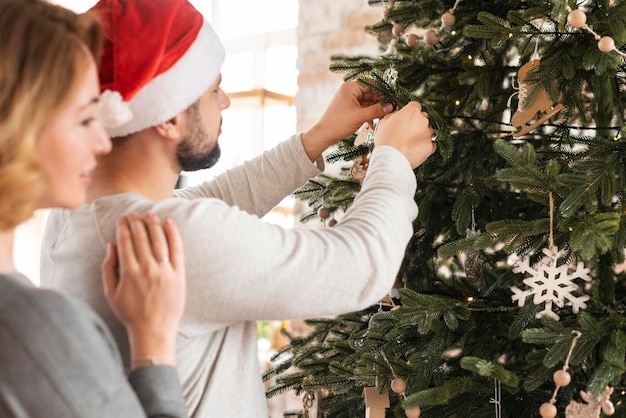 Vrouw en echtgenoot die boom met exemplaarruimte verfraaien