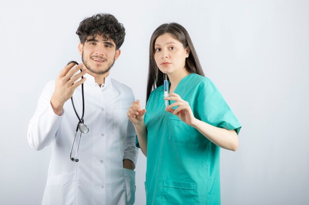 Vrouw en man artsen staan en kijken verrassend naar de camera.