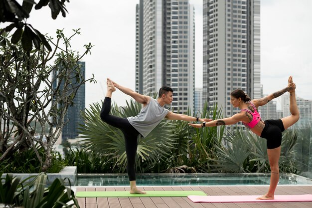 Vrouw en man beoefenen van yoga op de mat buiten naast het zwembad