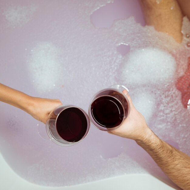 Vrouw en man handen met glazen drank in de buurt van water met schuim