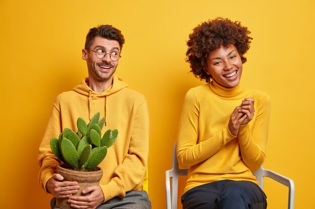 vrouw en man lachen en hebben plezier samen poseren op stoelen op geel