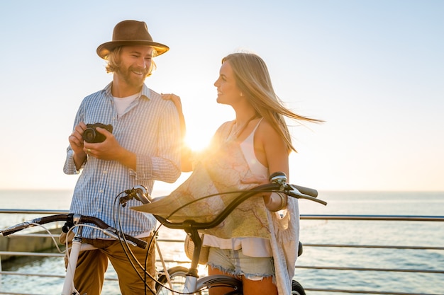Vrouw en man verliefd reizen op de fiets bij zonsondergang op zee
